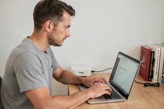 Homme configurant sa Freebox depuis un navigateur web sur ordinateur portable à son bureau à domicile