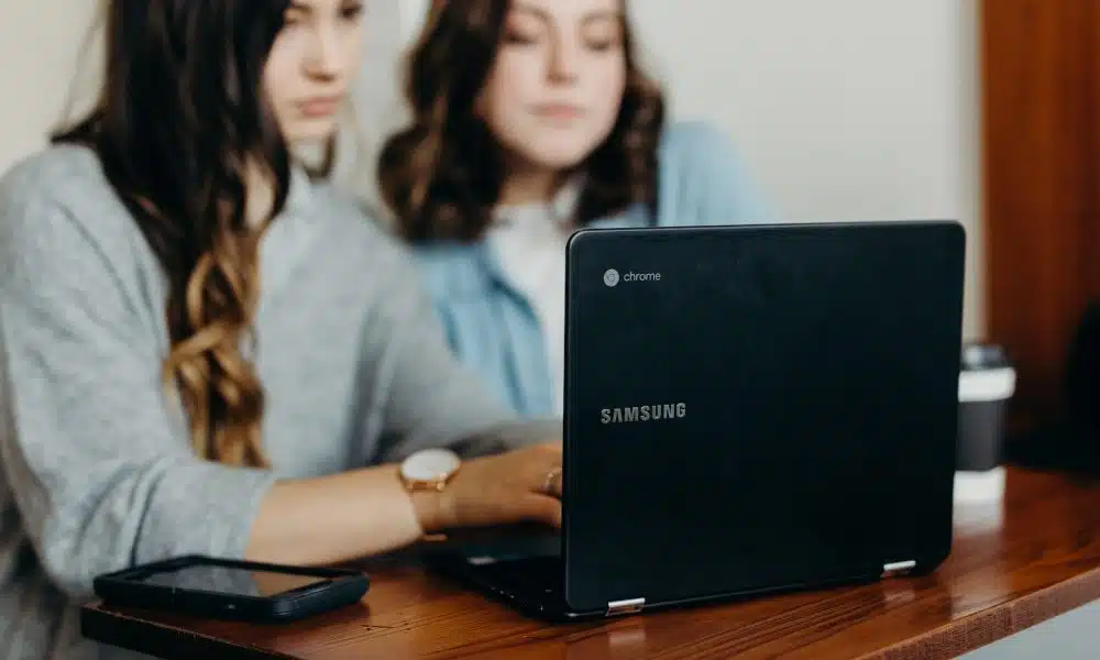 two woman using laptop