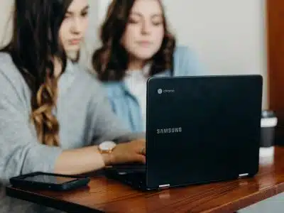 two woman using laptop
