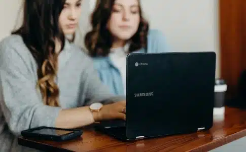 two woman using laptop