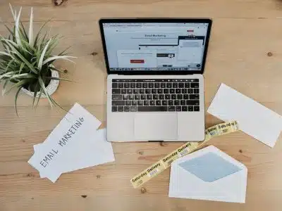 MacBook Pro beside white papers and plant